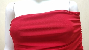 Close-up of red ruched mesh fabric on an asymmetrical off-shoulder evening dress
