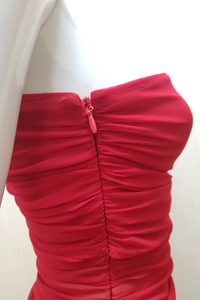 Detailed macro view of the seamless invisible zipper on the red pleated mesh evening dress