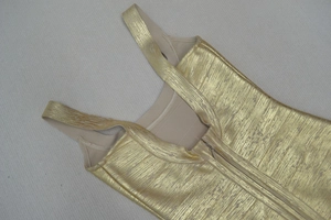 Détail d'une robe bandage dorée montrant le tissu métallique et la fermeture éclair