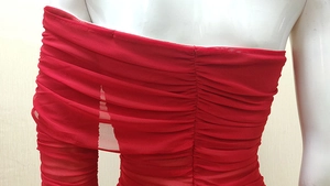 Detailed view of red ruched mesh fabric and tiered design on an off-shoulder evening dress