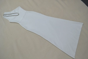 Détail d'une robe moulante blanche avec une élégante chaîne argentée tressée au décolleté