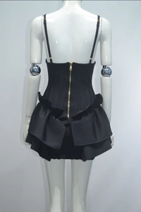 Detail showing the elegant multi-layer ruffled skirt and back golden zipper of the black dress
