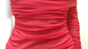 Close-up of vibrant red ruched mesh fabric on asymmetrical split evening dress