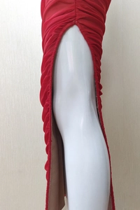 Detail of red ruched mesh dress showing textured fabric with asymmetrical pleats