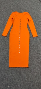Detail of bright orange ribbed knit dress with deep V-neck and decorative button down front