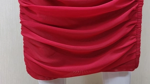 Detailed view of red pleated mesh fabric layers on the asymmetric slit evening gown