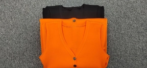 Detailed macro view of black and orange ribbed knit cardigans with V-neck button closure
