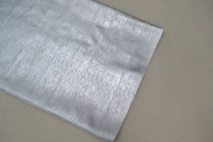 Détail d'un tissu métallique argenté avec texture brossée verticale et fini brillant