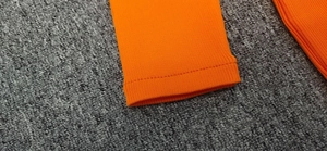 Detailed close-up of orange ribbed knit fabric showing neat stitching and texture