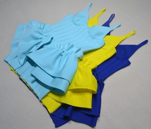 Detail of layered ruffle hem on colorful bandage strap dresses with ribbed texture
