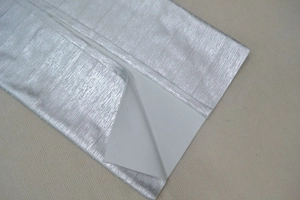 Détail du tissu métallique argenté montrant la texture brossée et la doublure blanche