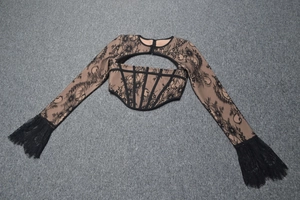 Dettaglio del crop top in pizzo con corsetto a stecche e frange sulle maniche lunghe