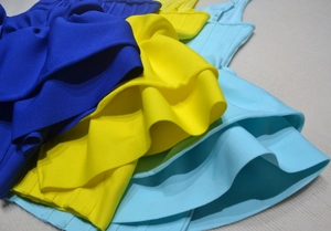 Close-up of layered ruffle edges on multi-color bandage dresses in blue and yellow