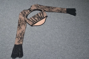 Dettaglio del crop top in pizzo nero con ritagli e pannelli trasparenti velati