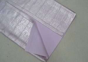 Détail du tissu à texture métallique argentée avec doublure violette et finitions soignées