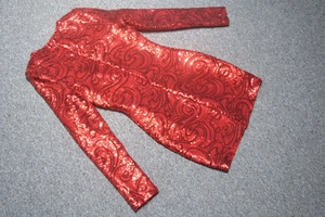 Détail de la robe courte à paillettes rouges et motifs de tourbillons noirs sur tapis