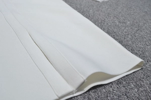 Détail du tissu en maille côtelée blanche de la robe montrant la texture et la finition