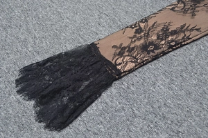 Dettaglio ravvicinato di intricati motivi in pizzo nero e polsini a strati sulla manica