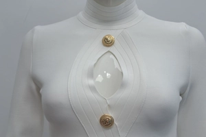 Detail des weißen Rippstrickkleides mit Brust-Cut-Out und goldenen Löwenkopf-Knöpfen