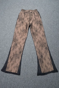Dettaglio dei pantaloni in pizzo a vita alta con fiori neri sovrapposti e fondo a zampa