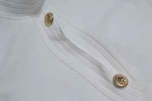 Details von weißem Bandage-Strickstoff mit dekorativen goldenen Löwenkopf-Knöpfen