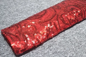 Détail du tissu à paillettes rouges avec motifs en spirale et éclat métallique