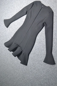 Détail d'une mini robe noire avec manches cloche, ourlet à volants et fermeture éclair invisible