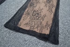 Dettaglio ravvicinato del pizzo floreale nero con motivi di rose e fodera rosa