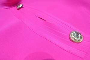 Detail von goldenen Löwenkopf-Knöpfen am rosaroten Rippstrick-Minikleid mit Relief