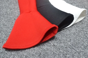 Détail des poignets évasés à volants sur une robe en maille rouge, noire et blanche