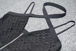 Détail de la robe bandage en résille noire avec motifs ronds et fermeture éclair argent