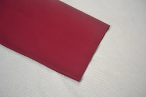 Détail rapproché du tissu de robe en dentelle bordeaux montrant la texture fine