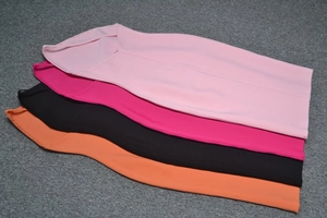 Dettaglio in piano di gonne a tubino elasticizzate in rosa, fucsia, nero e arancione