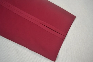 Détail d'une housse de coussin bordeaux avec fermeture portefeuille et texture fine