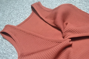 Close-up of ribbed knit texture and crossover pleated neckline on a sleeveless red-brown top