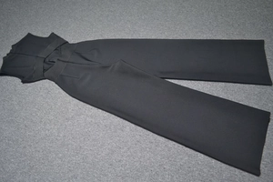 Détail d'une combinaison noire sans manches à jambes larges avec lacets croisés à la taille