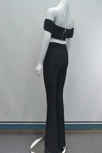 Dettaglio del top nero con spalle scoperte e zip dorata posteriore con pantaloni a zampa
