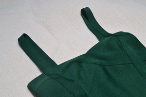 Detailed close-up of dark green bandage dress fabric showing textured horizontal knitting