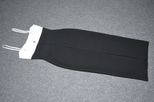 Dettaglio in piano di un abito bandage bicolore con eleganti fibbie dorate sulle spalline