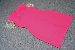Detailed view of silver metal chain tassels on the shoulders of a rose red bandage dress