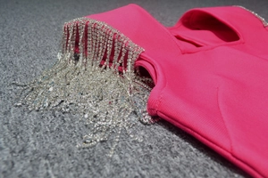 Detailed view of silver rhinestone fringe tassels on hot pink bandage dress shoulder