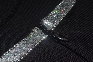 Macro view of colorful rhinestones along the metal zipper on black bandage dress