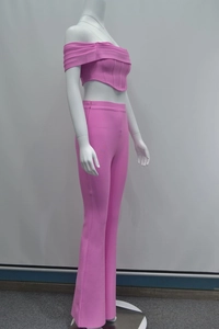 Vista laterale del top a corsetto rosa con spalle scoperte e dei pantaloni a zampa alta