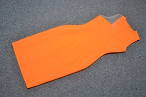 Détail d'une robe moulante orange à une épaule avec mesh et fermeture éclair au dos