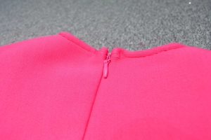 Close-up of invisible back zipper and stitching on rose pink bandage dress fabric