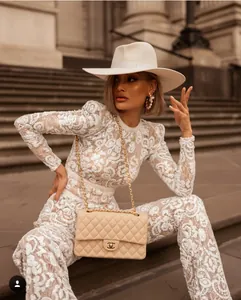 Macro detail of intricate white lace embroidery and beadwork on long sleeve jumpsuit outfit
