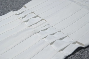 Detailed close-up of white mesh bandage dress featuring elastic textured fabric and cutout design