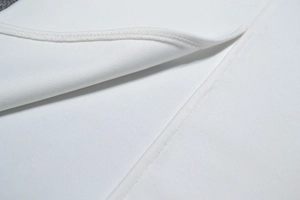 Close-up of precise stitching and mesh patchwork on white bandage dress fabric