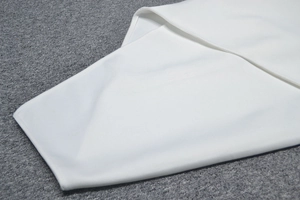 Close-up of white bandage dress fabric showing fine stitching and high-quality edge finish