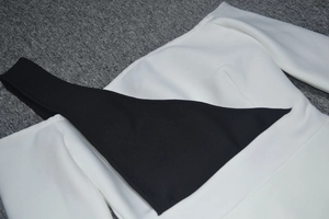 Detail view of the black and white asymmetric contrast shoulder strap on a sleek bandage dress